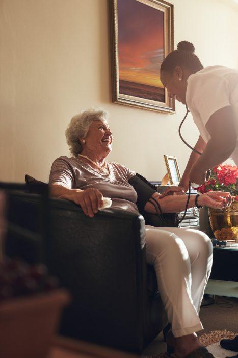 Nurse measuring blood pressure of senior lady patient